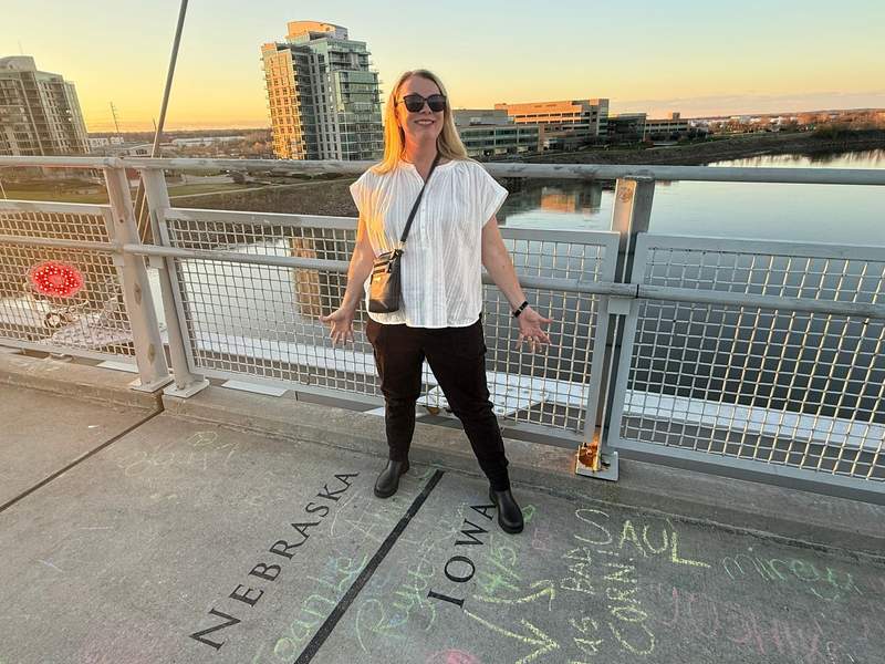 A woman stands on Omaha’s famous Bob Bridge straddlling two states, Nebraska and Iowa.
