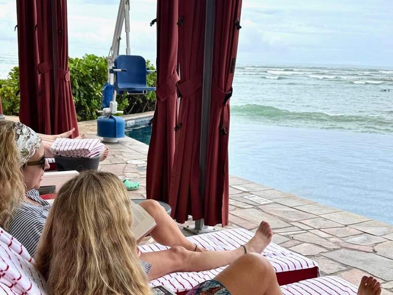 Two women in a cabana rental overlooking the pool and the ocean at Sheraton Waikiki.