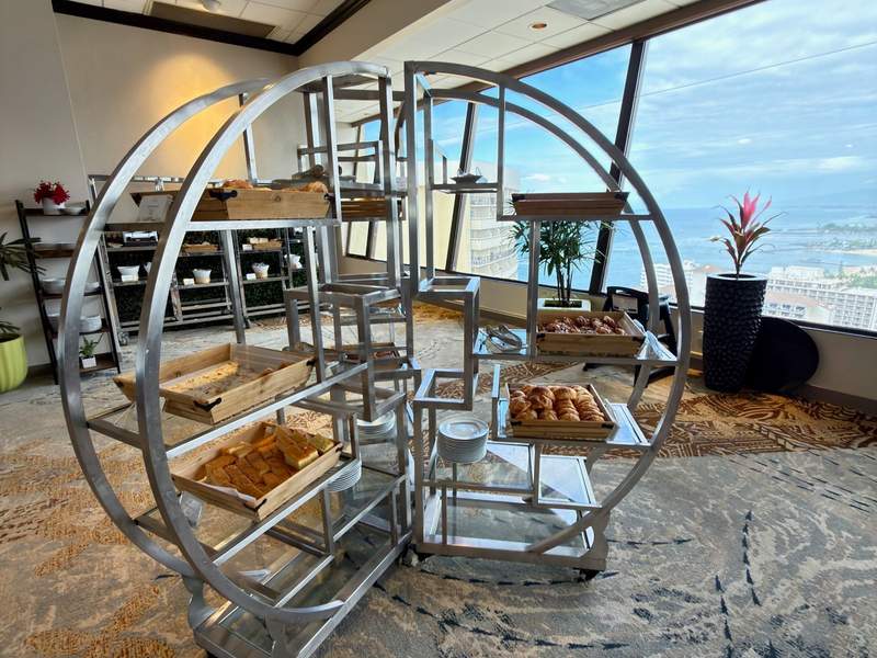 Silver metal wheel with shelves that hold various kinds of breads and croissants at Kai Market at the Sheraton Waikiki.