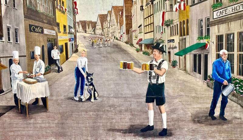 Man in short lederhosen holds three steins in each hand filled with beers of different shades. Two chefs behind table. Woman in jeans and white shirt holds collar on her dog.
