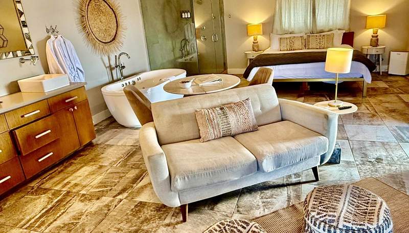 Big walk in shower fills one corner of the living space next to the king size bed and behind the soaking tub. Sofa for two anchors middle of the room.