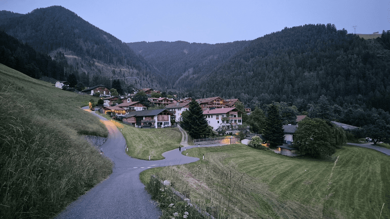 Buildings, including Sonnwies Resort, set amid green fields and mountains.