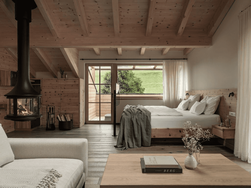 A guest room featuring blonde wood, a wood stove, soft lighting and a porch