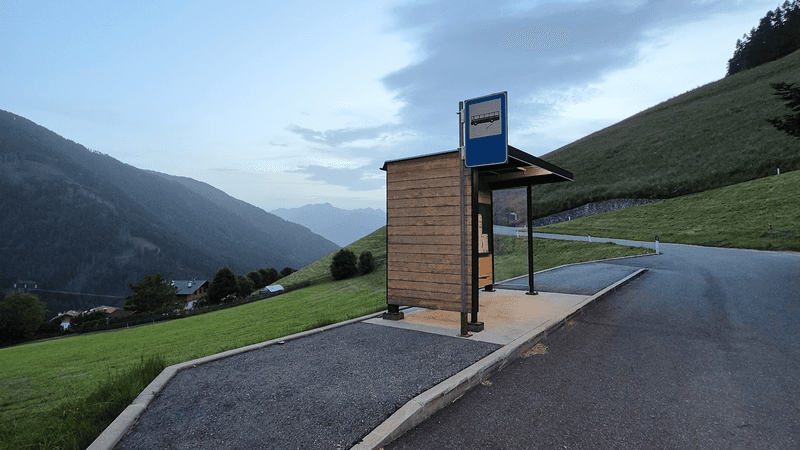 A rural bus stop near Sonnwies Resort surrounded by green rolling hills. 