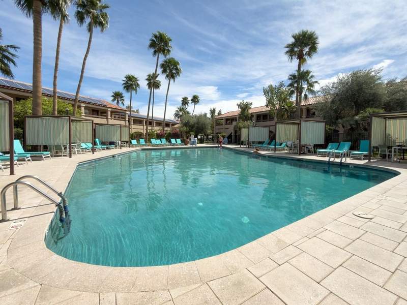 Outdoor swimming pool at La Fuente Inn and Suites with palm trees and guest rooms surrounding the courtyard.
