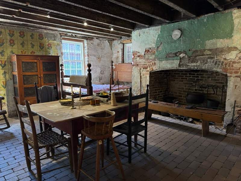 Large fireplace and table with brick floor showing the original kitchen of the house in the Davenport Museum 