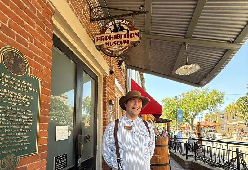 Young man in period dress and hat standing in front of the American Prohibition Museum. 
