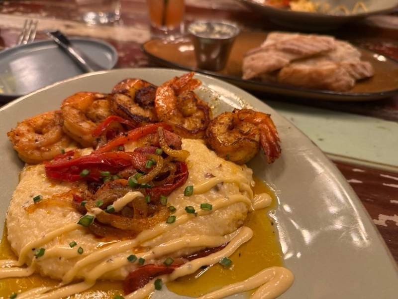 Shrimp and Grits dish on a white plate with peppers and onion on top. 