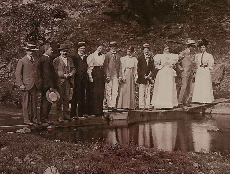 a group of people in old fashioned clothes on a bridge. 