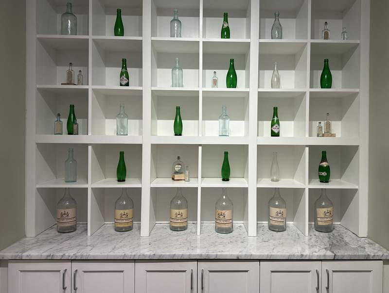 Green and cleear bottles on shelves. 