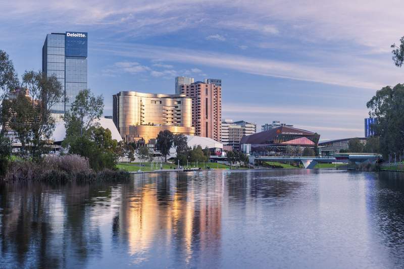Scenic shot of the city of Adelaide with skyscrapers behind a body of water.