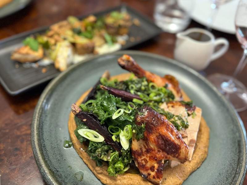 A beautifully-plated dish of chicken and greens on a plate in a restaurant.