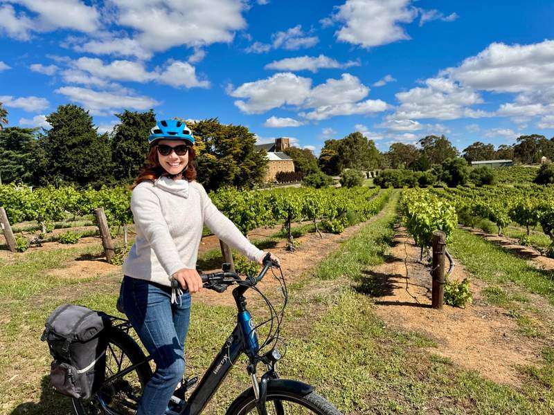 Woman sitting on an e-bike with vineyards in the background.