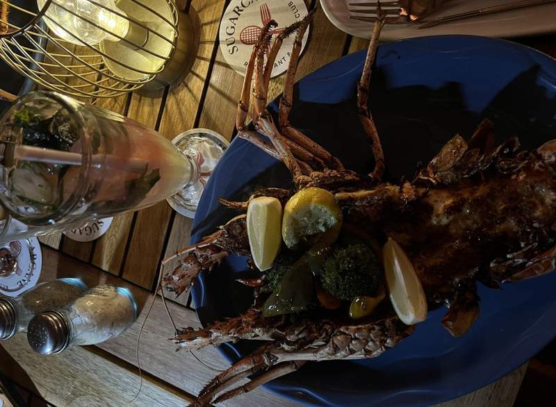 Sugarcane’s Whole Grilled Lobster is plated on a dimly lit table