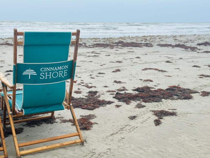 Reserved seats daily at the beach for a nice relaxing afternoon. Beach chair labeled Cinnamon Shore on the beach.