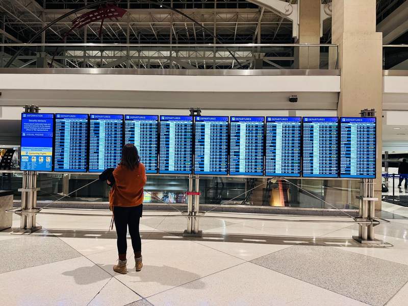 woman standing in airport looking at the incoming flights. 