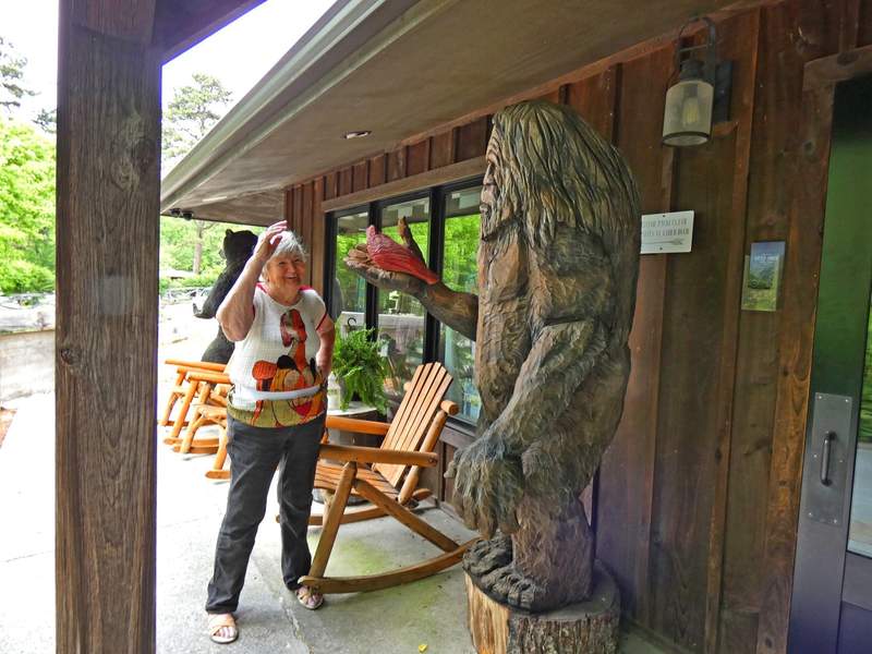 Woman greeting a wood carving of Bigfoot in front of Little Arrow Outdoor Resort