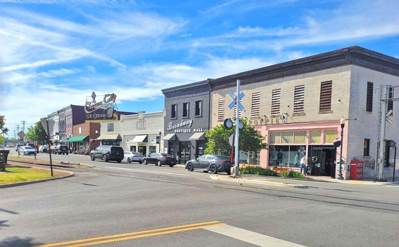 A downtown street in Cookeville with a Cream City Ice Cream sign, many businesses and a train track.