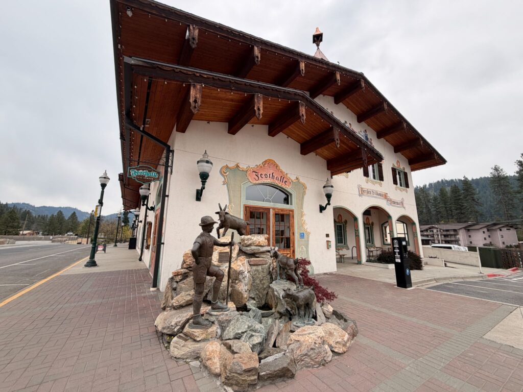 Large German-style building with a statue of an alpine mountain climber with a goat.