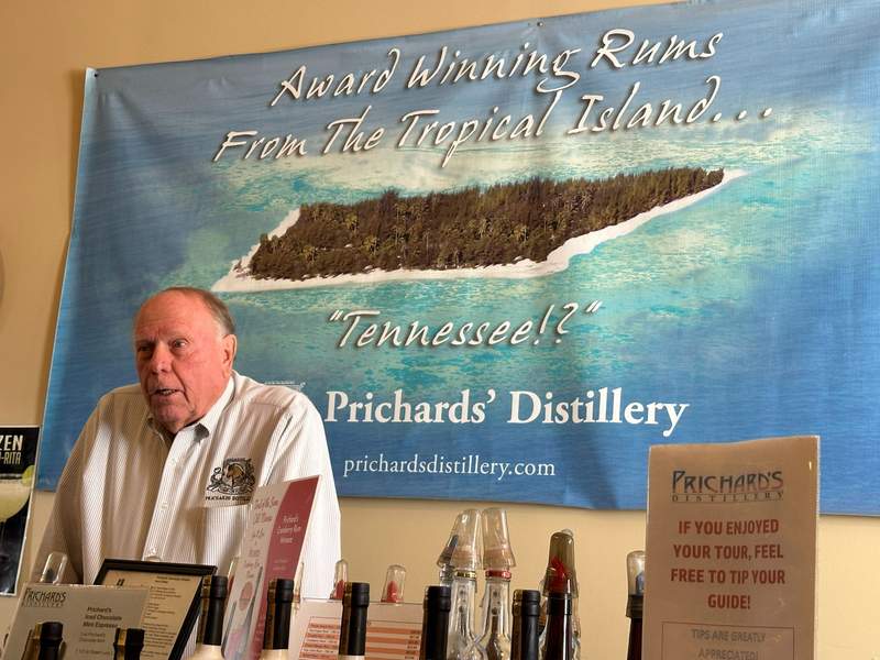 A man in a white shirt in front of a poster.
