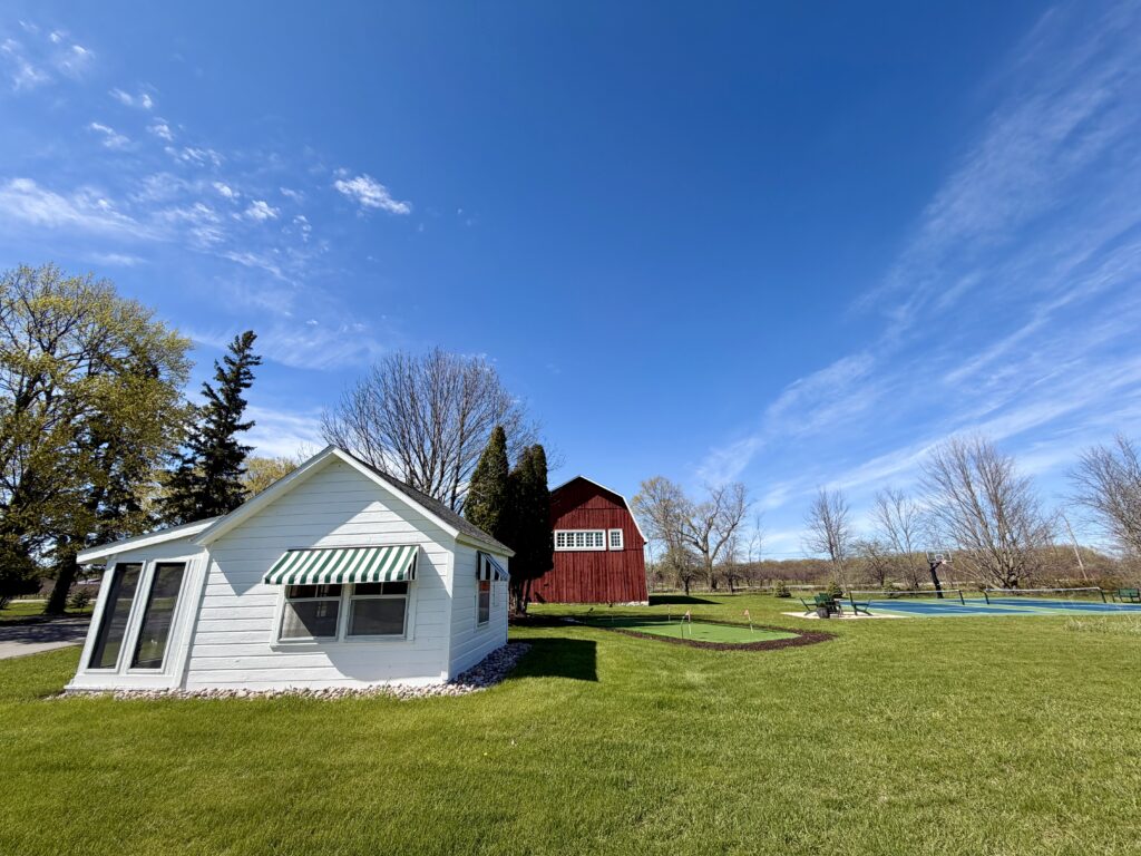 Red barn and white cottage with pickleball courts and fire pit at Loma Cottages in Door County, Wisconsin
