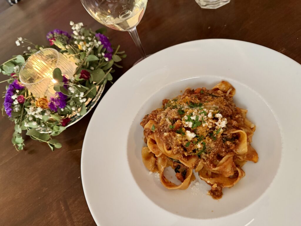Tagliatelle with meat sauce on a white plate served at Osteria Tres Tasso, a classic Italian restaurant in Door County