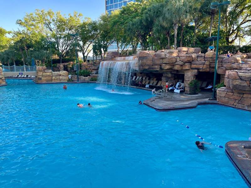People swim in a large pool with a waterfall feature at the Dolphin hotel. 