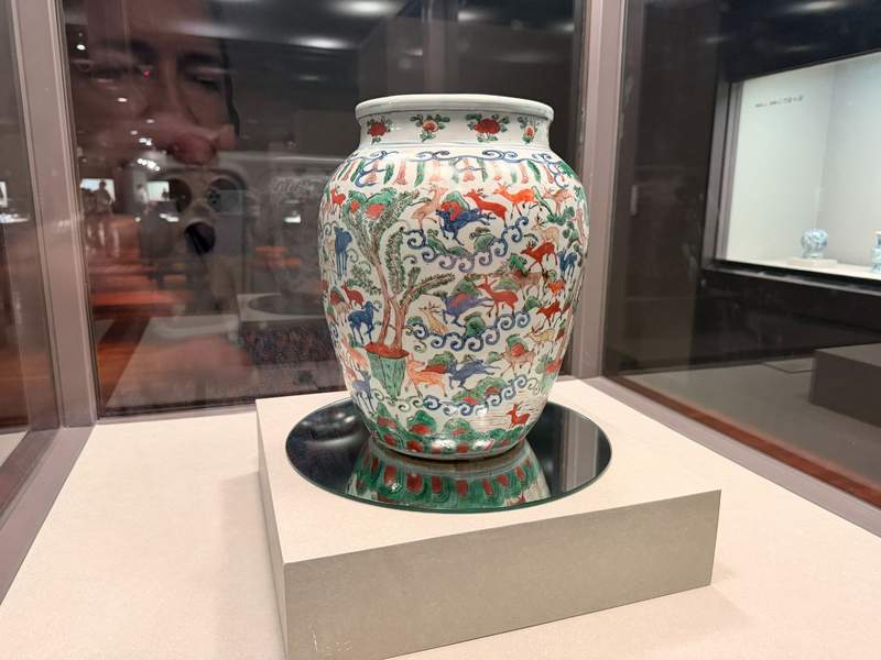  Ceramic vase with 100 deer on it displayed in a museum case.