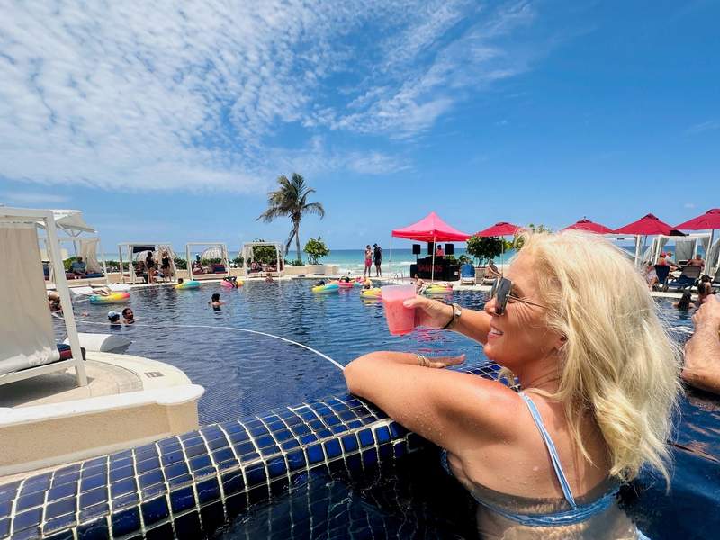 Woman relaxing with a frozen drink in the infinity pool at Sandos Cancun, a Cancun all inclusive adults only resort overlooking the Caribbean Sea