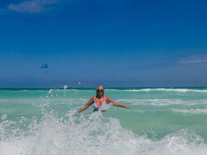 Woman standing in the turquoise ocean waves at Sandos Cancun, a Cancun all inclusive adults only resort with a beachfront location in Cancun.