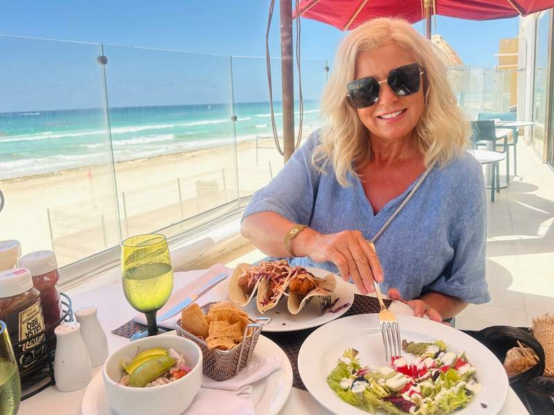 Woman enjoying tacos and lunch with ocean views at Sandos Cancun, a Cancun all inclusive adults only resort in Cancun’s Hotel Zone.