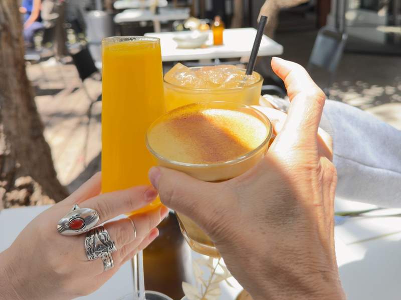 Three orange and yellow drinks clinking glasses.