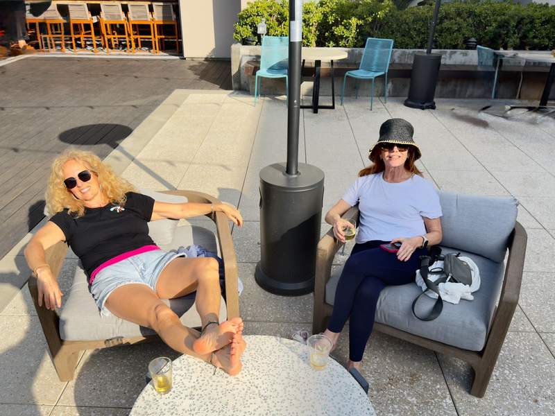 Kim and a friend are relaxing in patio chairs sipping happy hour cocktails.