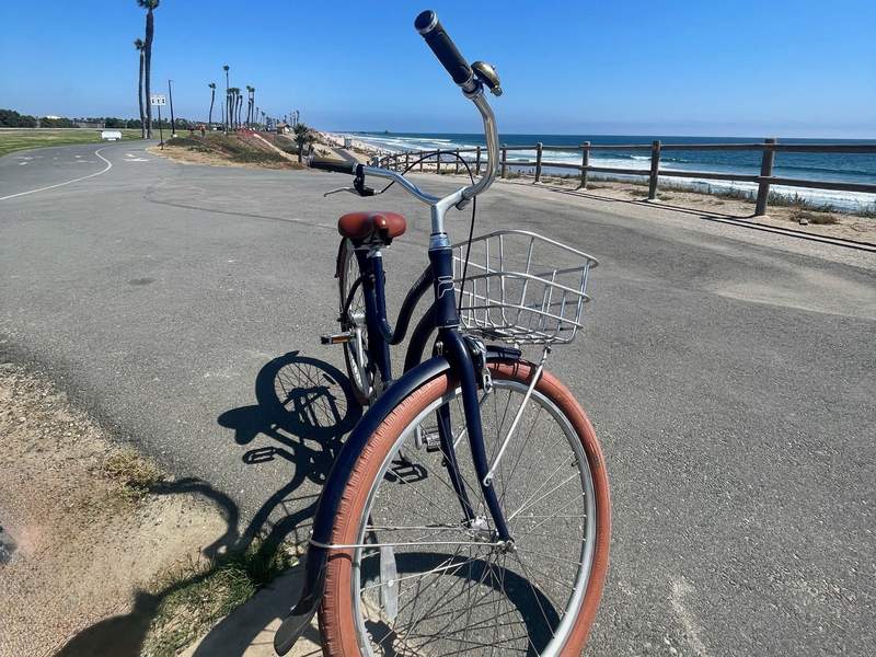 Black bicycle with brown tires parked on the bike path overlooking the Pacific Ocean.