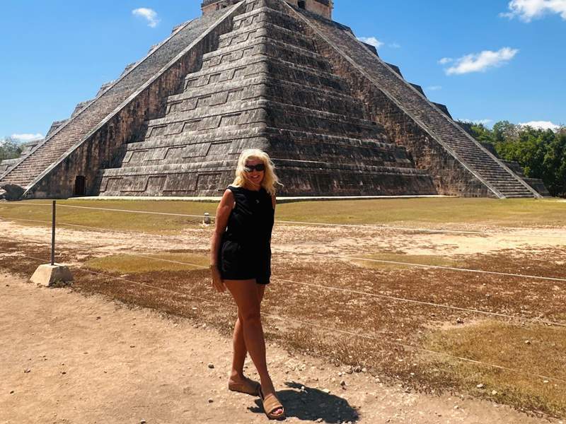 Woman standing in front of the Chichén Itzá pyramid during a day tour from Playa del Carmen all inclusive resort in Mexico.