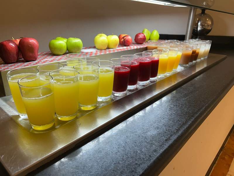 A line-up of fresh fruit and juices on the breakfast buffet in bright, colorful colors, including yellow, orange and red.