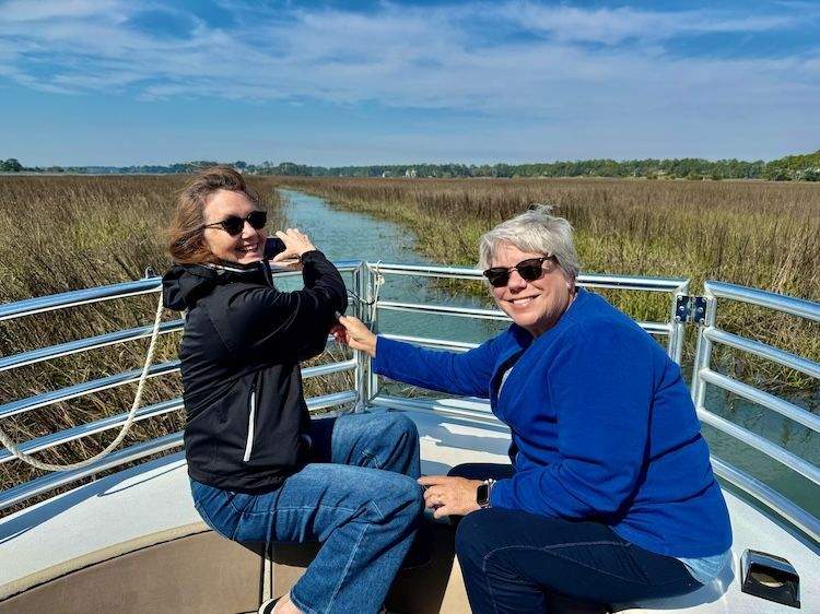 Two women in the bow of a boat with a marsh view