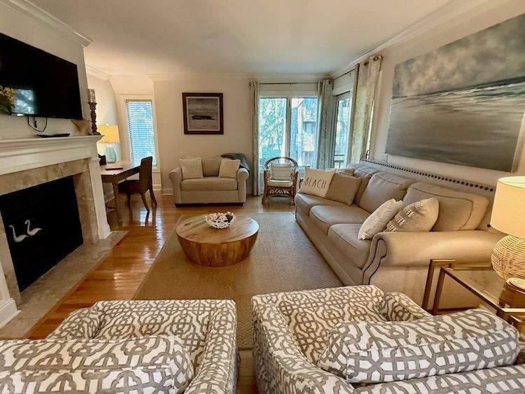 Villa living area in neutral tones with fireplace, sofa and chairs.