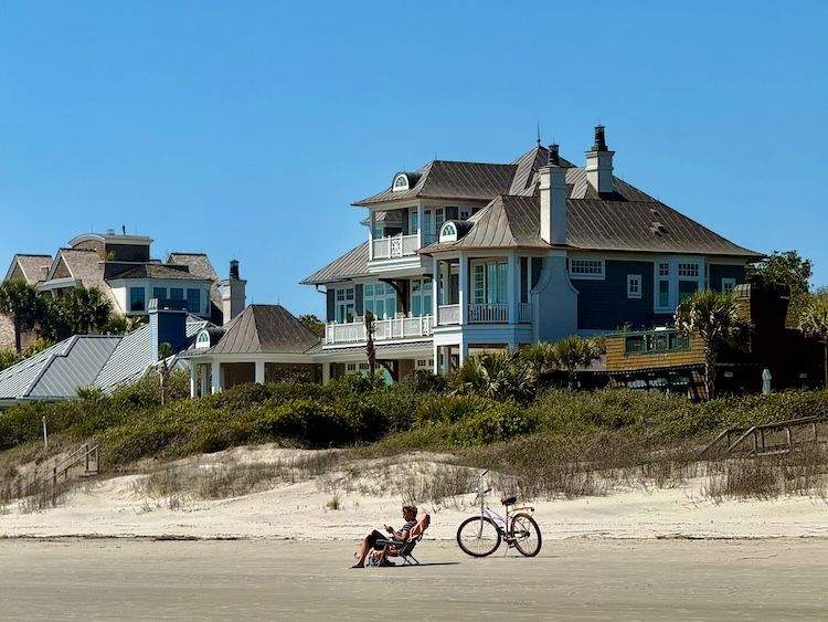 Beachfront private home, showing a person seated in a beach chair and a bike on the sand.