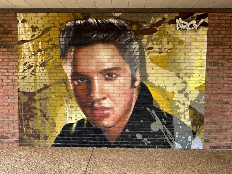 A colorful mural of Elvis Presley face on a brick wall in Tupelo.