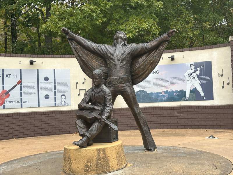 Two statues of Elvis showing him as a boy and as a famous singer.