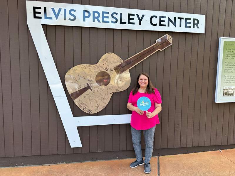 A lady in a pink top in front of the Elvis Presley Center.