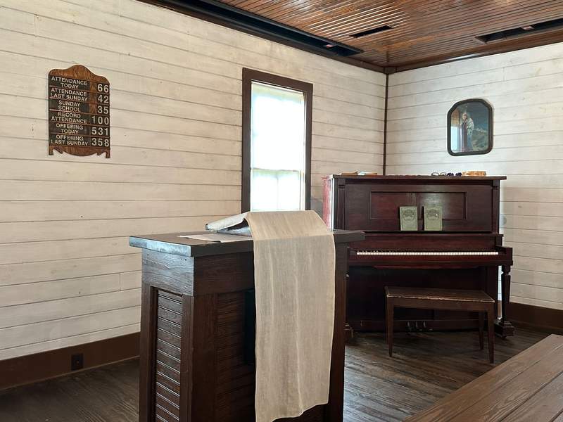 Inside a church with a wooden floor, pulpit, and piano.
