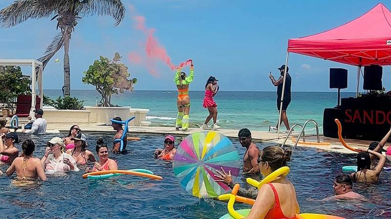 Guests enjoying a colorful pool party with DJs and entertainment at Sandos Cancun