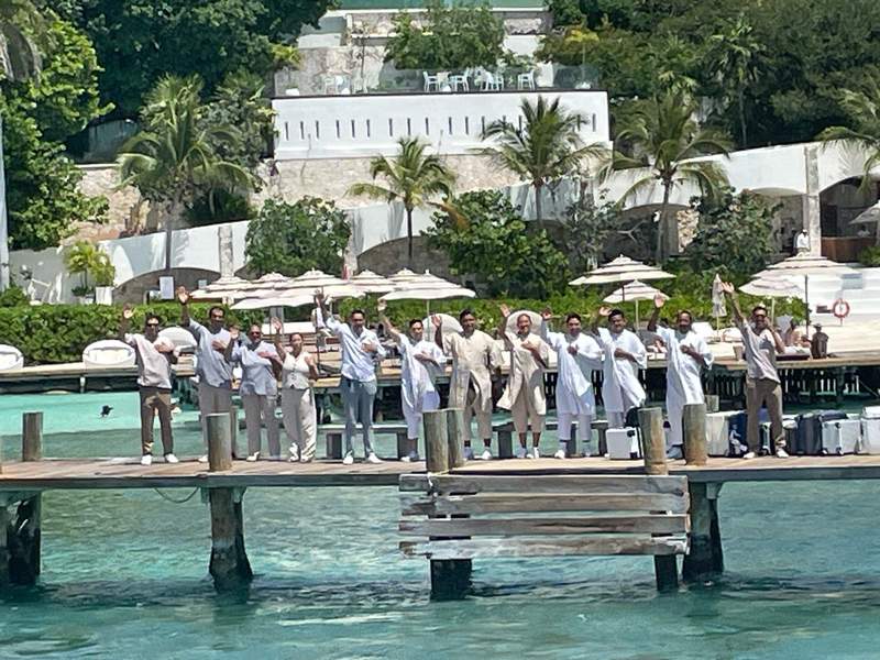Twelve Staff on the pier at Impression Isla Mujeres by Secrets waving in welcome.