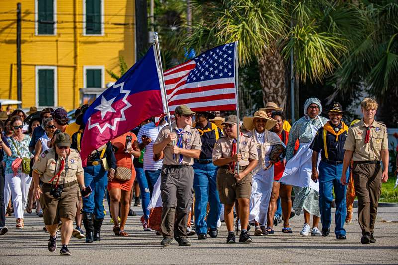 A group of people walking down the street with flags.