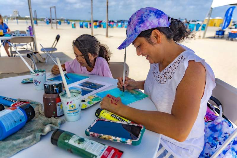 A woman and girl working ona craft at a table.
