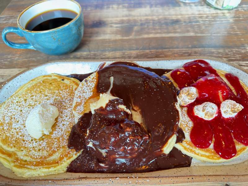 A vibrant brunch spread at Prelude Breakfast Bar in Fayetteville Arkansas, featuring a pancake flight with unique flavors, served in a bright and lively restaurant interior.