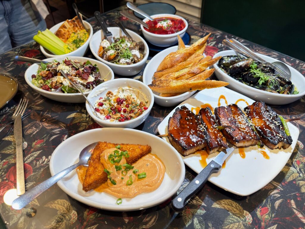 A gourmet food spread at Leverett Lounge in Fayetteville Arkansas, featuring the unique Mel's Diner deep-fried garlic cheese grits appetizer served with remoulade sauce