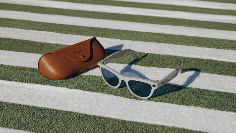 Ray-Ban Meta AI Glasses and case lying on a green and white striped rug.